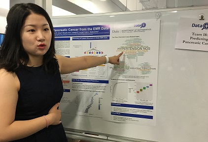 student pointing to research poster on board