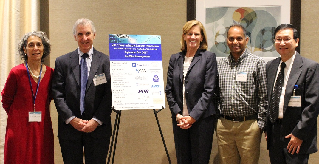 5 speakers / people standing by the Duke-Industry Statistics Symposium poster