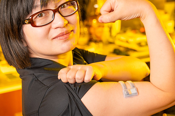 Xiaoyue Ni flexing her bicep to which is attached an electronic monitoring patch.