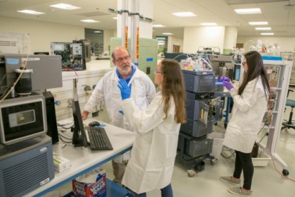 three people working in a lab with mass specrometer