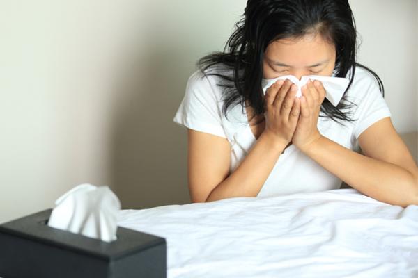 woman sneezing into tissue