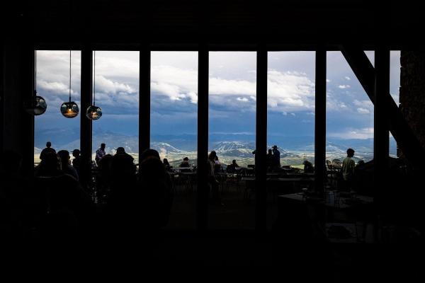 Photo of silhouetted people sitting at tables with a backdrop of a mountain landscape