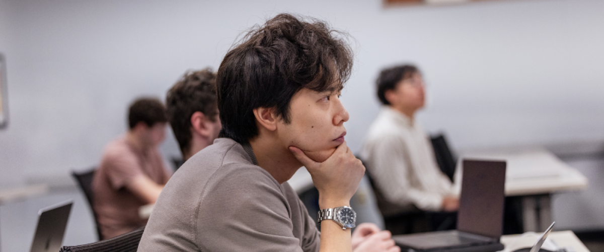 Student at desk looking engrossed with hand under chin