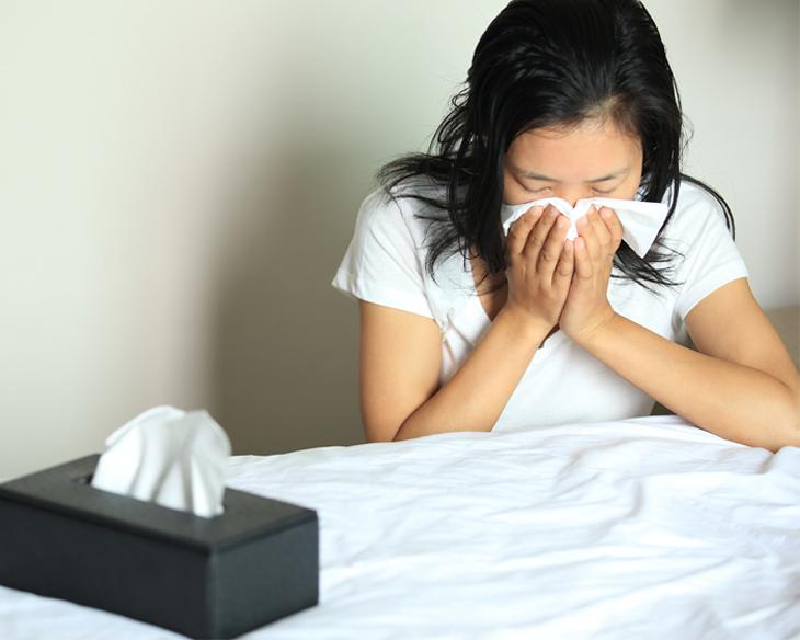 woman sneezing into tissue