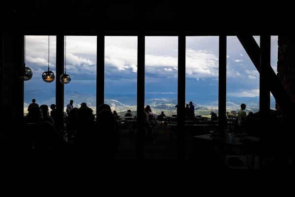 Photo of silhouetted people sitting at tables with a backdrop of a mountain landscape