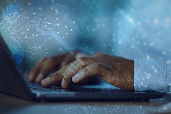 Photo of hands at a laptop overlaid with computer code