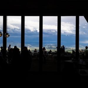 Photo of silhouetted people sitting at tables with a backdrop of a mountain landscape