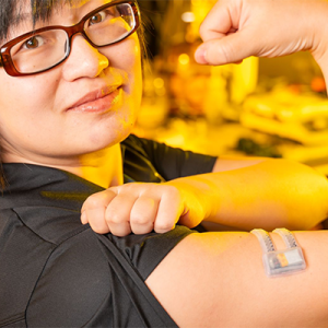 Xiaoyue Ni flexing her bicep to which is attached an electronic monitoring patch.